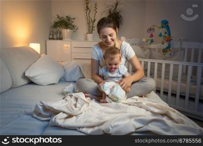 Toned image of mother changing diapers to her baby at night