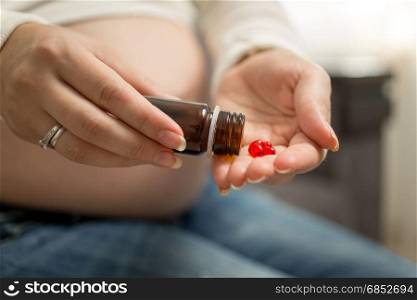 Toned image of pregnant woman emptying bottle with medicines on hand