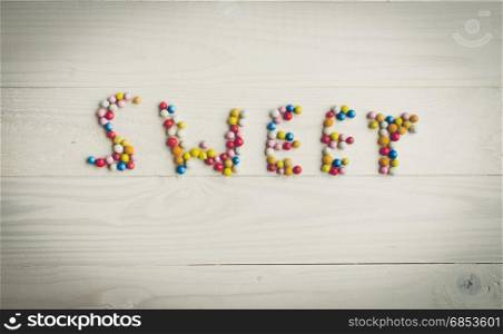 Toned image of word Sweet made of colorful candies on white background