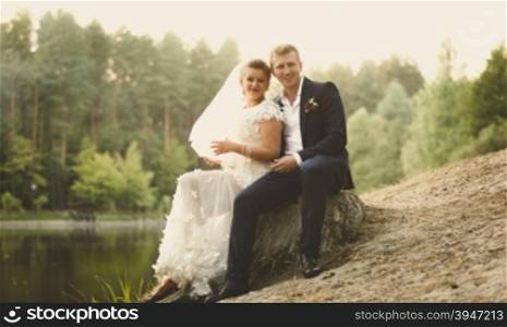 Toned in retro style photo of beautiful just married couple relaxing on the riverbank at forest