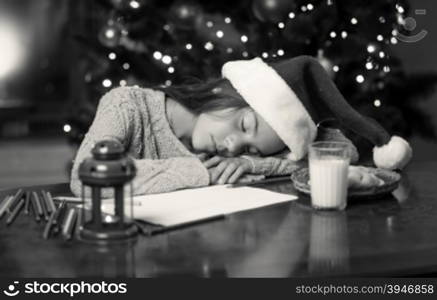 Toned monochrome portrait of cute girl fell asleep while writing letter to Santa