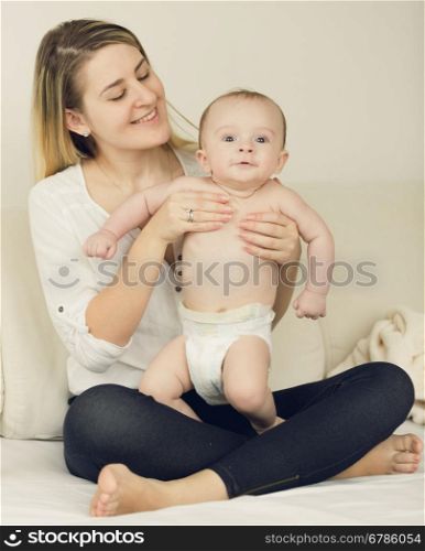 Toned photo of 6 month baby boy relaxing on bed with his mother