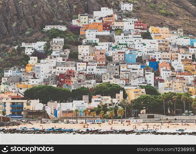 Toned photo of beautiful small town with colorful buildings between high mountain and ocean beach, Tenerife, Spain. Toned image of beautiful small town with colorful buildings between high mountain and ocean beach, Tenerife, Spain