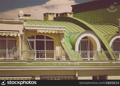 Toned photo of beautiful terrace under green metal roof at classic building