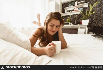 Toned photo of beautiful woman lie in bed with cup of coffee