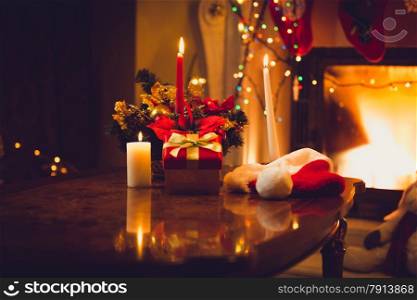 Toned photo of burning candles, fireplace and giftbox at christmas eve