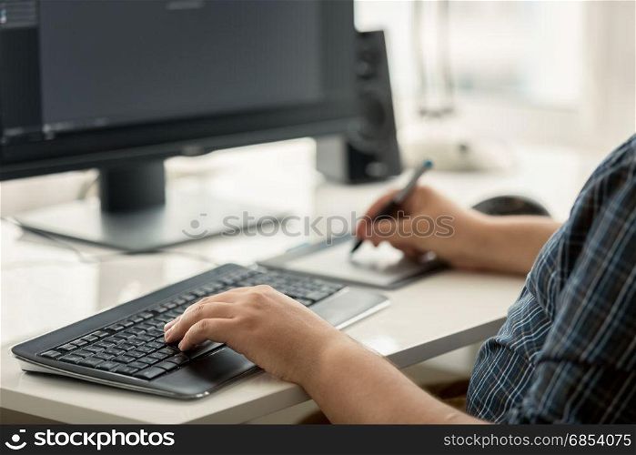Toned photo of graphic designer using tablet and keyboard at work