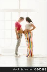 Toned photo of happy young pregnant couple touching by stomachs