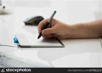 Toned photo of male graphic designer drawing on digital graphic tablet