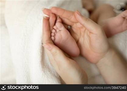 Toned photo of newborn baby feet in mothers hands