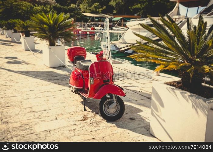 Toned photo of retro red scooter parked at sea port