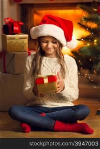 Toned photo of smiling girl sitting on floor and looking at Christmas presents