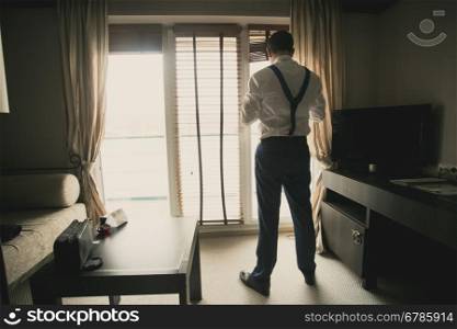 Toned photo of young businessman dressing up at hotel room