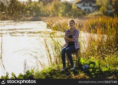 Toned photo of young woman relaxing by the lake at sunset