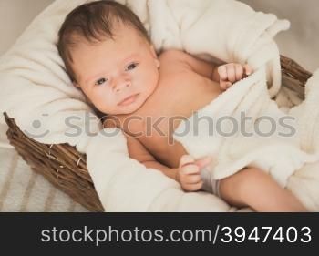 Toned portrait of beautiful baby boy lying in wicker basket