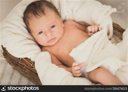 Toned portrait of beautiful baby boy lying in wicker basket