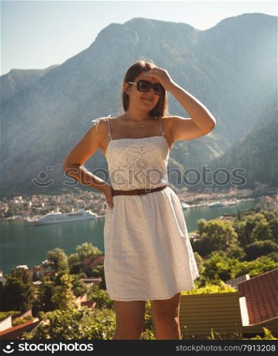 Toned portrait of beautiful brunette woman against high mountain