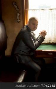 Toned portrait of elegant businessman traveling in old train