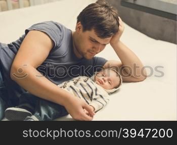 Toned portrait of happy father and baby boy lying on bed