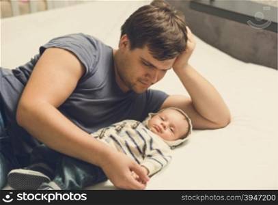 Toned portrait of happy father and baby boy lying on bed