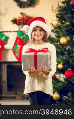 Toned portrait of happy girl in santa cap posing with Christmas gift box