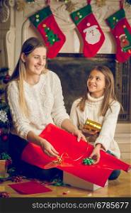 Toned portrait of happy young mother and cheerful daughter decorating Christmas presents