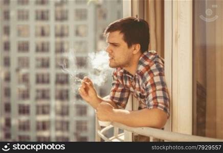 Toned portrait of hipster guy smoking cigarette and drinking coffee