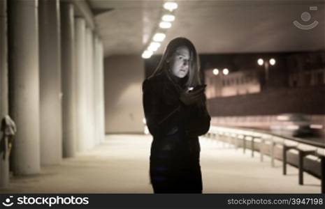Toned portrait of lonely woman using mobile phone at night on street