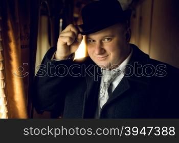 Toned portrait of man in vintage clothes posing in train
