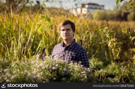 Toned portrait of man working at garden and cutting flowers