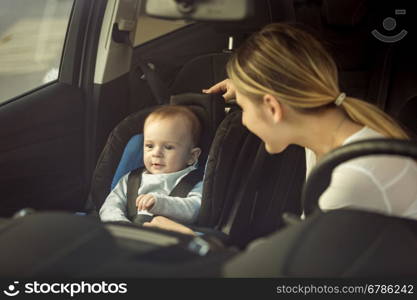 Toned portrait of mother and baby boy sitting in car on front seats