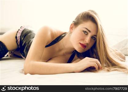 Toned portrait of sexy woman with long hair posing on bed