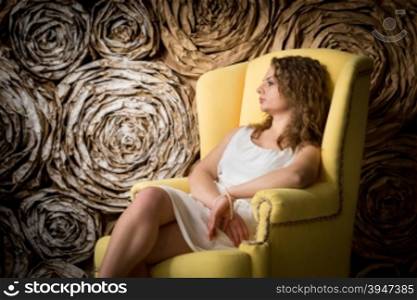 Toned portrait of sexy young woman relaxing in big armchair