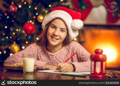 Toned portrait of smiling girl writing letter to Santa