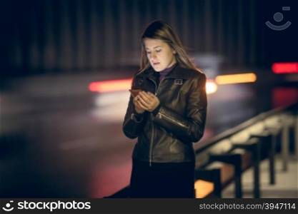 Toned portrait of woman with smartphone at night highway