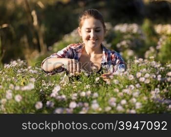 Toned portrait of young woman cutting flowers at garden