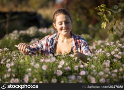 Toned portrait of young woman working at garden and cutting flowers