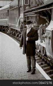 Toned retro photo of elegant man waiting on platform for train