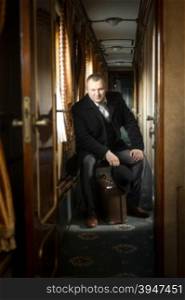 Toned shot of man in vintage suit posing in old train