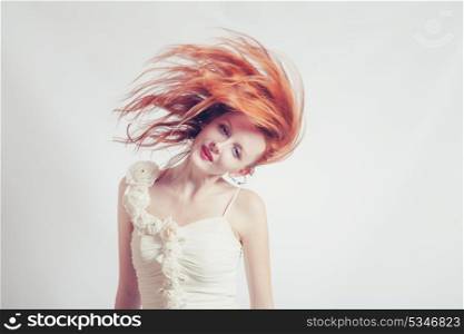 Toned shot of red haired expressive emotional female with flying hair on studio background