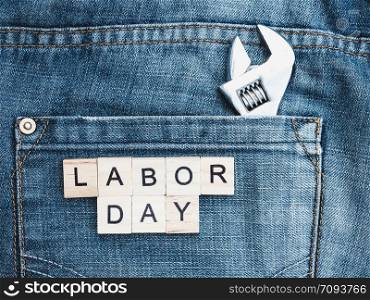 Tools and wooden letters with the inscription LABOR DAY on the background of a blue jeans pocket. Top view, close-up. Preparation for the celebration of Labor Day. Tools and wooden letters with the inscription LABOR DAY