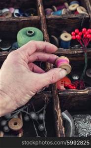 Tools for needlework. hand with spool of sewing thread choosing accessories for needlework