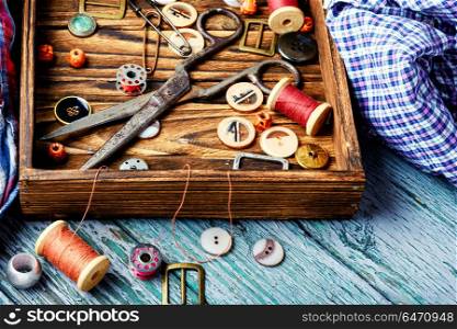 Tools for needlework. Wooden box with buttons from clothes, threads and scissors.Sewing accessories.
