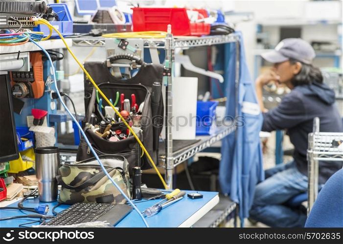 Tools on table with male technician in background at electronics industry