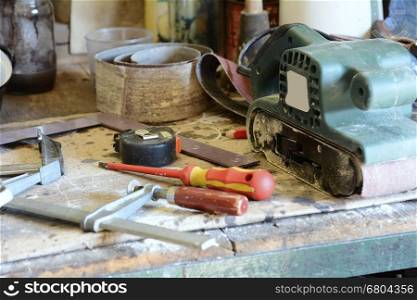 Tools on the workbench, screwdriver, meter and grinder.
