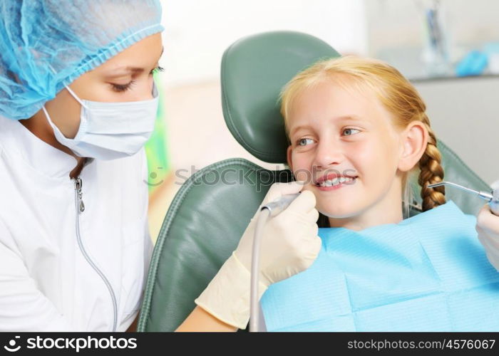 Tooth check. Cute smiling girl in at dentist sitting in armchair