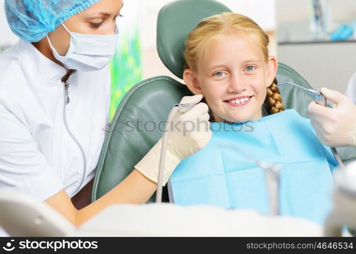 Tooth check. Cute smiling girl in at dentist sitting in armchair