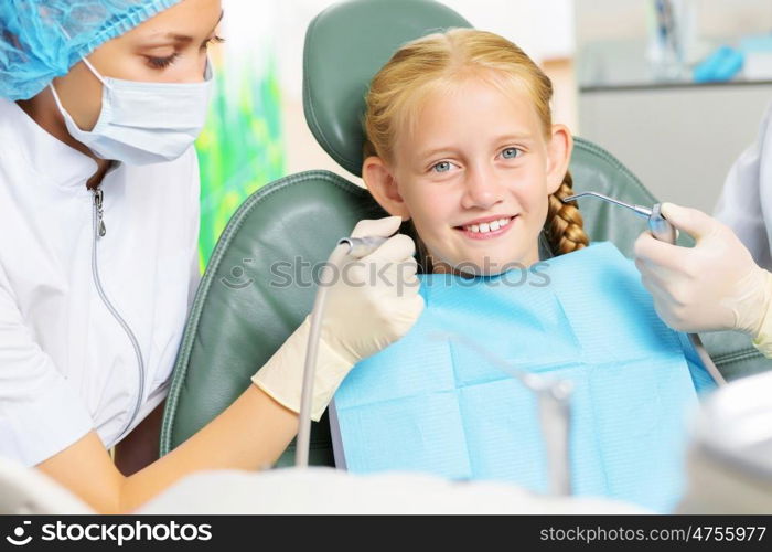 Tooth check. Cute smiling girl in at dentist sitting in armchair