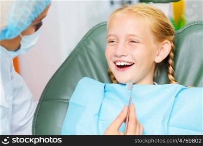 Tooth check. Cute smiling girl in at dentist sitting in armchair
