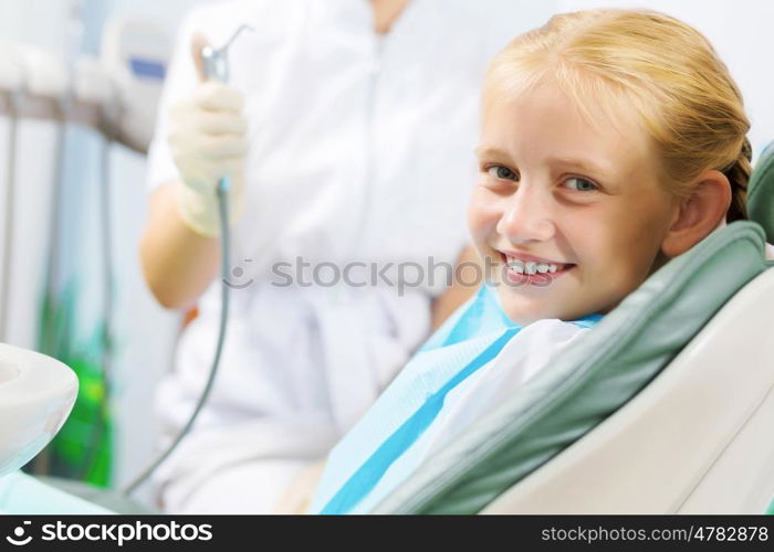 Tooth check. Cute smiling girl in at dentist sitting in armchair